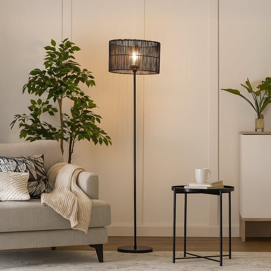Black floor lamp with cylindrical rattan shade beside beige sofa in modern living room warm ambient lighting.