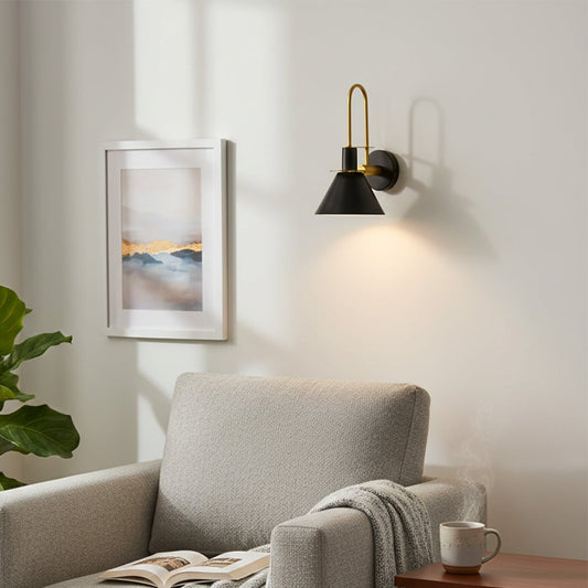 Modern black metal spotlight wall light creating cozy reading corner ambiance with warm interior lighting.