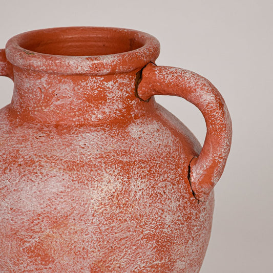 Closeup of terracotta ceramic vase showcasing weathered surface matte finish and traditional double handle design.