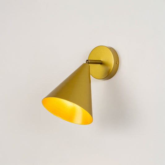 Gold metal wall light with cone shade emitting warm glow ideal for modern bedroom or hallway wall decor placement.