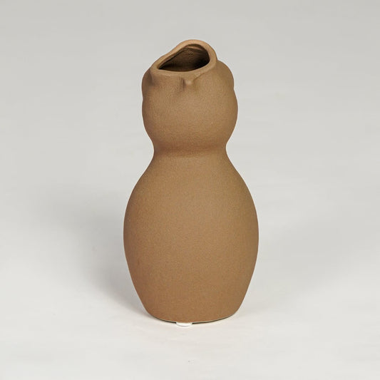 Brown ceramic sculpted vase with smooth organic silhouette isolated on clean white background for modern decor styling.