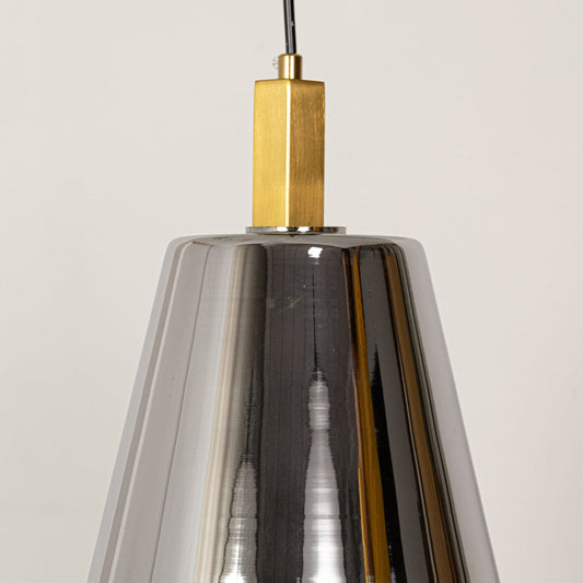 A closeup view of the smoked glass pendant light showing the detailed reflective surface and brass fitting with soft light creating a warm highlight.