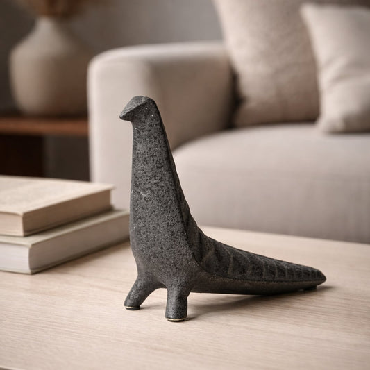 Dark grey ceramic abstract animal decor sculpture placed on wooden table in modern living room styling setup.