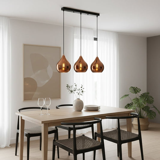Modern copper metal pendant light trio with glossy teardrop shades hanging from a sleek black bar creating a warm elegant room ambiance.