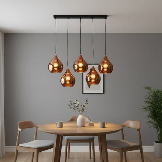 Modern copper pendant cluster with five glossy teardrop shades hanging from a long black ceiling bar creating a warm elegant focal point in the room.
