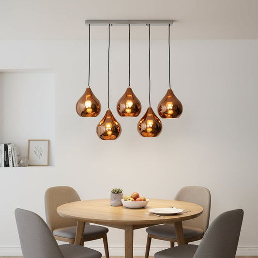 Modern copper pendant cluster with five glossy teardrop shades hanging from a silver ceiling bar creating a warm elegant focal point in contemporary interiors.