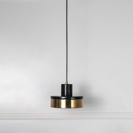 Black and gold pendant light with cylindrical design and hanging cord placed against neutral wall background enhancing stylish modern lighting decor appeal.