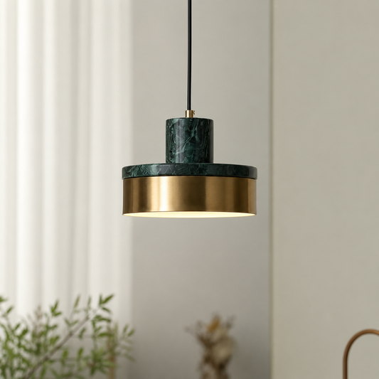 A modern pendant light with a dark green marble top and a brushed gold metal shade, suspended by a black cord against a neutral indoor background.