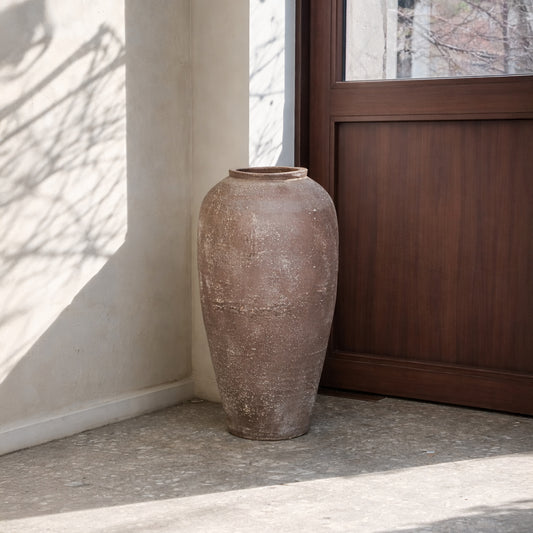 Lifestyle image of brown ceramic floor vase for modern living room corner decor with rustic textured finish.