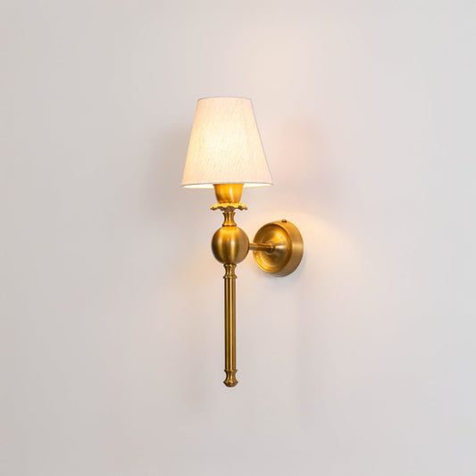 Elegant brushed gold metal traditional wall sconce light turned on to show a bright glow through a pleated fabric shade.