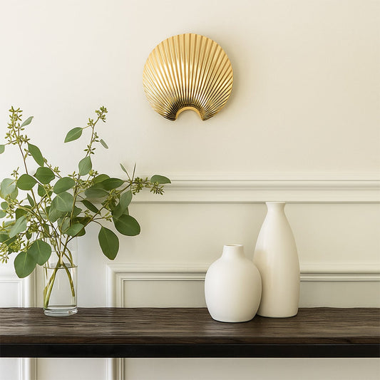 A gold shell shaped decor piece displayed in a soft lifestyle setting offering a modern elegant look that enhances any interior space beautifully.