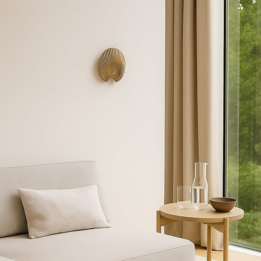 A gold decorative shell piece displayed on a clean wall creating a minimal lifestyle look with soft shadows and a modern sculptural feel that enhances elegant home styling.