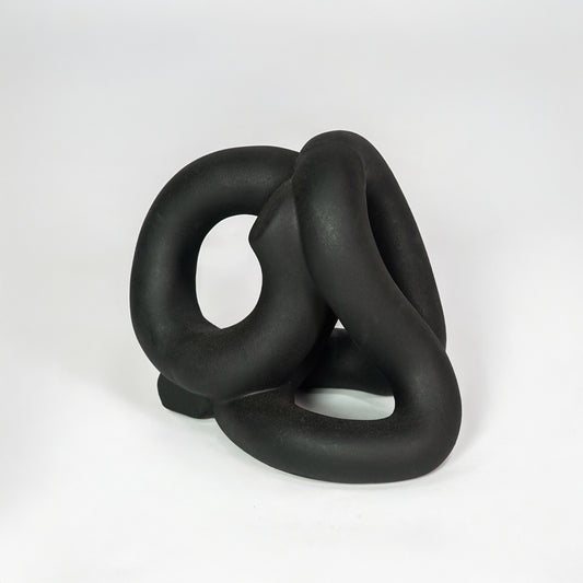 Black abstract ceramic sculpture on white background for elegant contemporary home decor styling.
