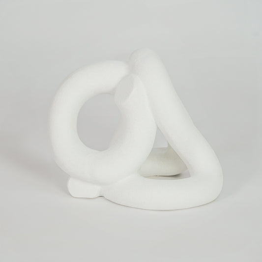 White abstract ceramic sculpture on white background for elegant modern shelf decor styling.
