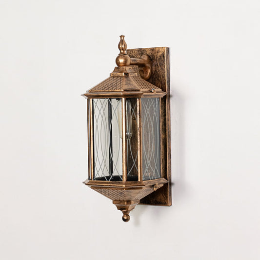 Antique gold metal outdoor wall lantern switched off on white background emphasizing detailed glass panels and metal finish.
