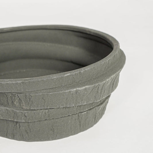 Black ceramic serving bowl with rustic textured stone finish perfect for elegant dining table centerpiece and contemporary home decor styling.