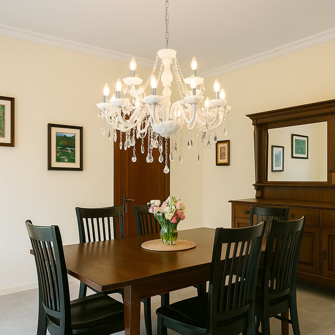 White chandelier with crystal details glowing in a stylish living room with sofa flowers and modern wall art.