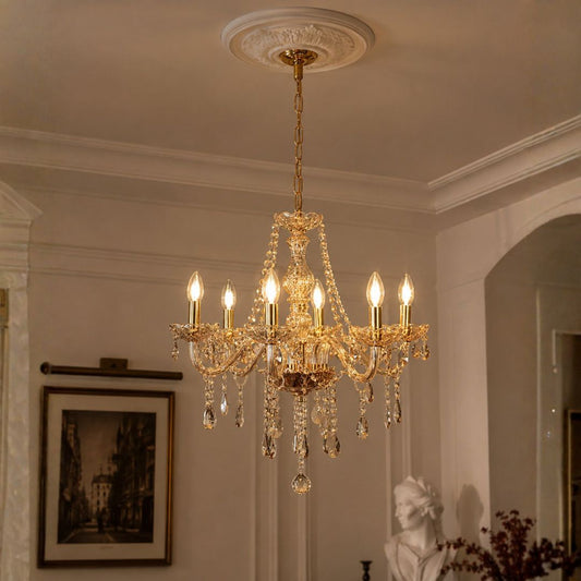 A multi-light crystal chandelier with gold-toned metal arms and hanging clear glass teardrop prisms, suspended from a decorative ceiling medallion in an elegant interior room.
