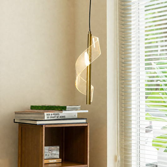 A modern spiral pendant light with a gold metal frame and clear glass shade, hanging in a room corner next to a window with white blinds.