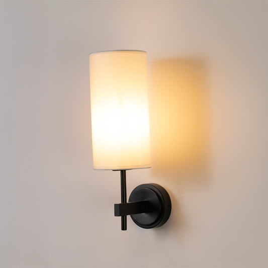 Contemporary wall light in black metal finish with fabric shade for bedroom or living decor lighting white background.