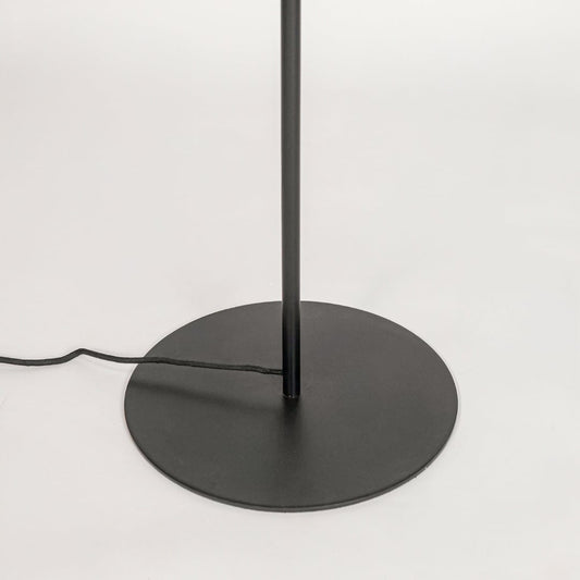 Closeup of round black metal base with slim sturdy stand highlighting stable modern floor lamp for home Decor.