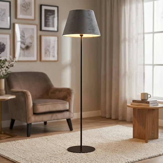 Modern black metal floor lamp with grey velvet shade styled in minimal contemporary living room corner setting.