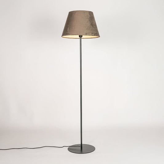 Black metal floor lamp glowing warmly through dark grey fabric shade on white background for cozy home Decor.