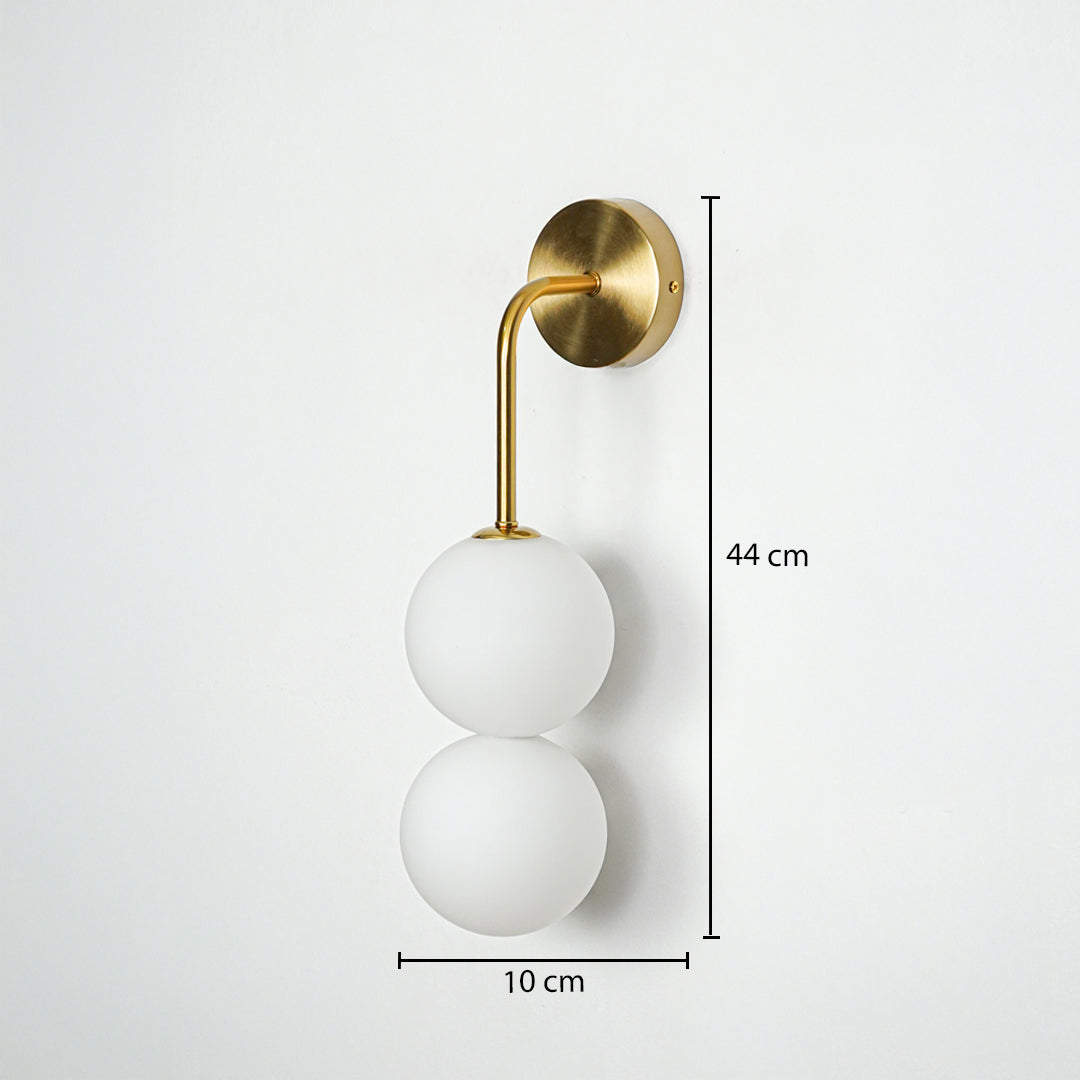 Gold wall light with double frosted glass globes on white background with dimensions modern vertical lighting ideal for bedroom decor.
