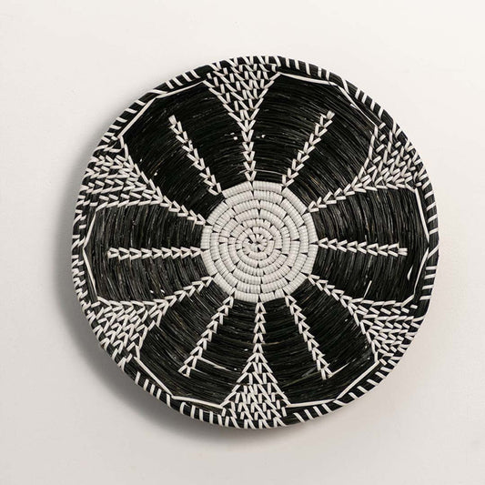 Black and white woven decorative wall basket with radial geometric pattern for artistic wall styling and home decor.