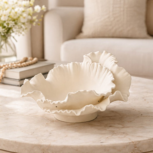White ceramic ruffled decorative bowl displayed on table creating graceful and contemporary interior decor accent.