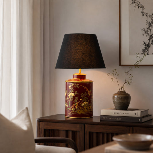 Amber glass table lamp with black fabric shade creating warm ambient lighting on wooden side table in elegant interiors.