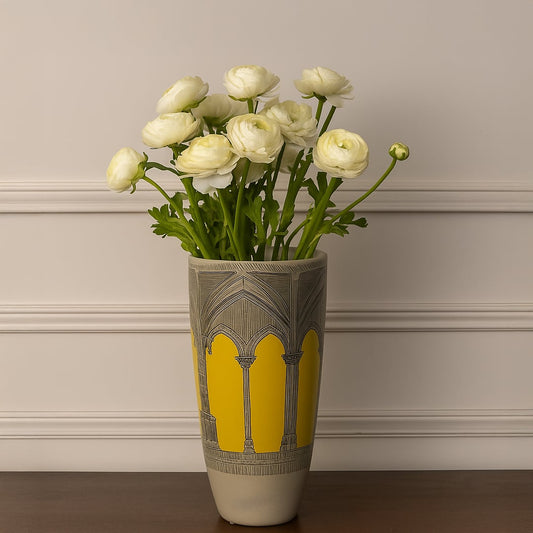Yellow and grey ceramic vase with arch pattern holding white flowers styled on wooden table for modern living room decor.