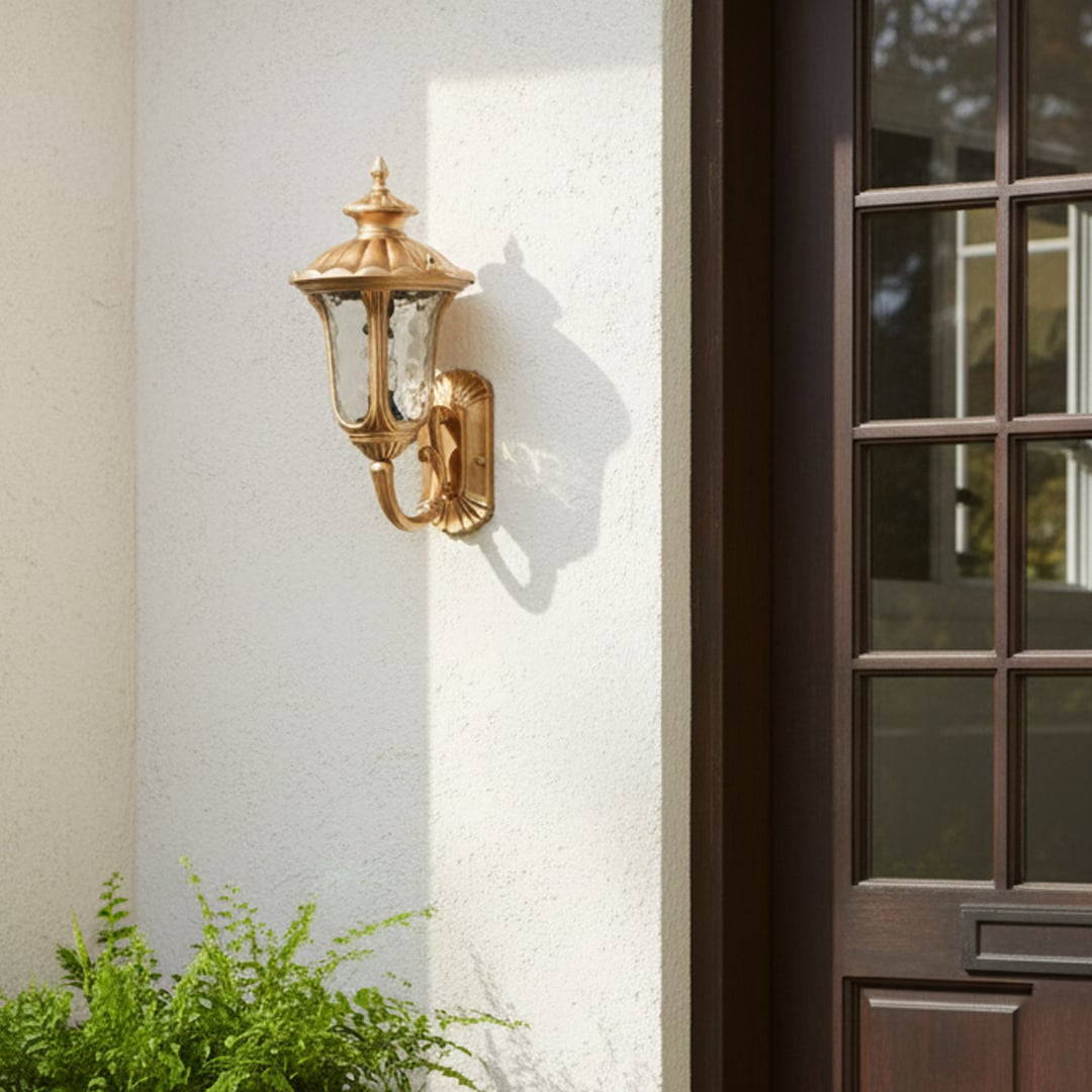 Gold outdoor wall light mounted beside entrance door on white exterior wall adding classic elegance and welcoming curb appeal to residential facade.