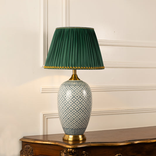 Grey patterned ceramic table lamp with green pleated shade displayed on a side table creating sophisticated ambient lighting.