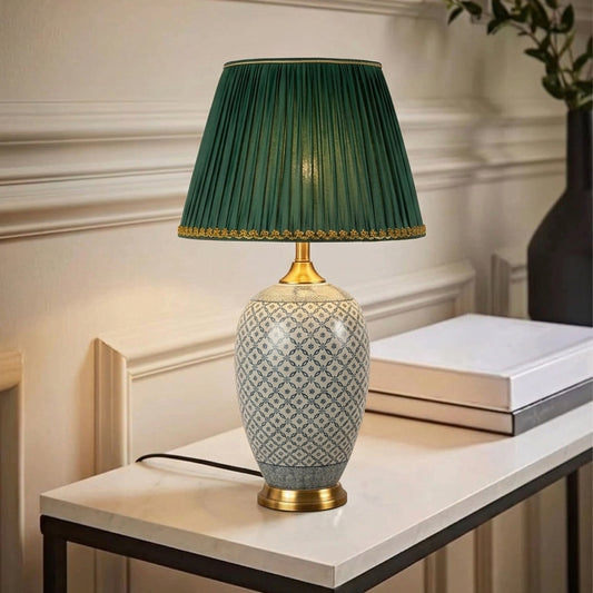 Elegant ceramic table lamp with a green pleated shade placed on a carved wooden side table beside a beige sofa in a warm classic living room.