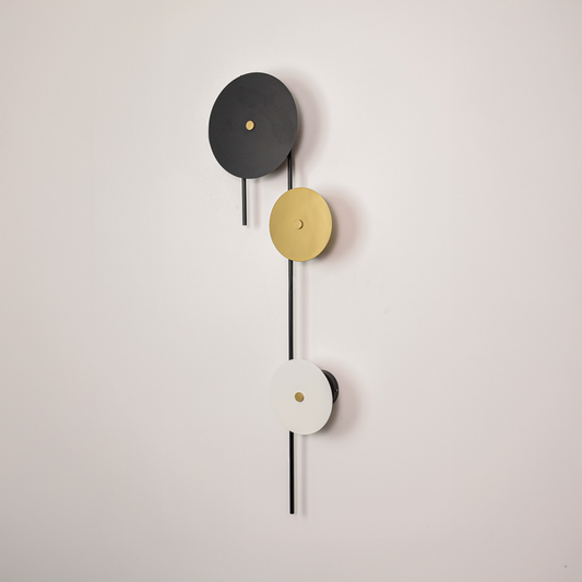 Wall light off on white background showcasing vertical black bar with round discs in black gold and white for clean minimalist product presentation.