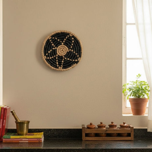 Handwoven round wall basket styled in a warm kitchen space above a counter with books plants and wooden jars adding a natural earthy Decor accent.
