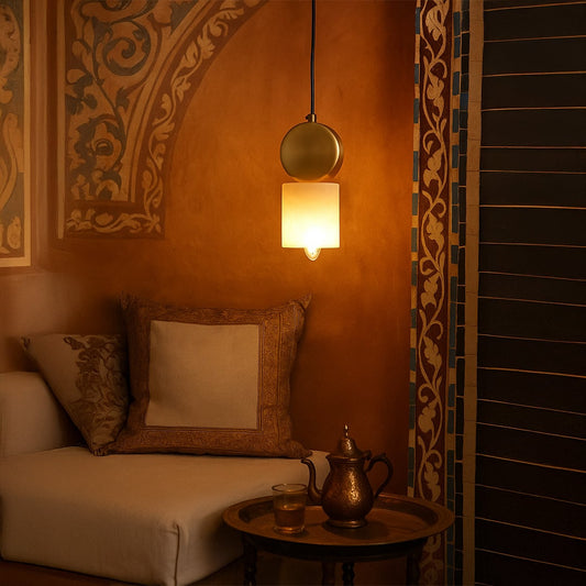 Gold pendant light with frosted glass shade glowing warmly styled in traditional living room interior with cozy wall design.