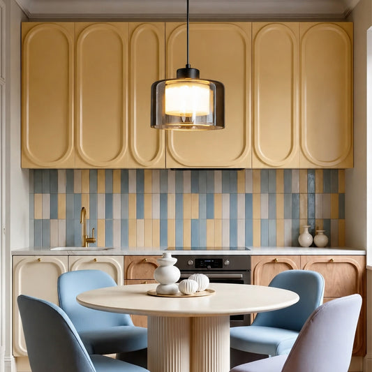 A modern kitchen interior with cream and beige wavy upper cabinets, a blue and beige striped tile backsplash, a round dining table, and four blue and lavender chairs under a hanging pendant light.