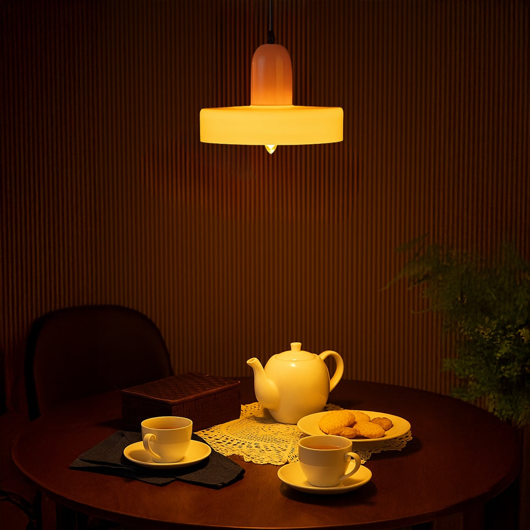 Illuminated layered metal pendant light casting soft warmth across contemporary dining interiors.