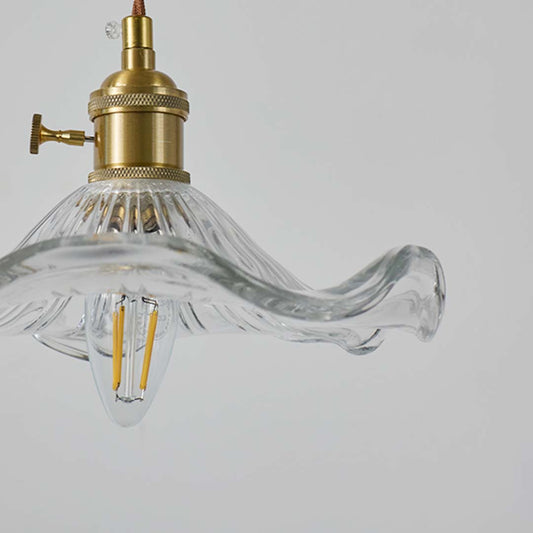 Closeup of clear wavy glass and brass metal pendant light showcasing premium craftsmanship.