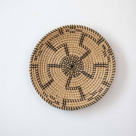 Minimalist handcrafted woven seagrass wall hanging basket decor plate featuring a black geometric pattern on white.