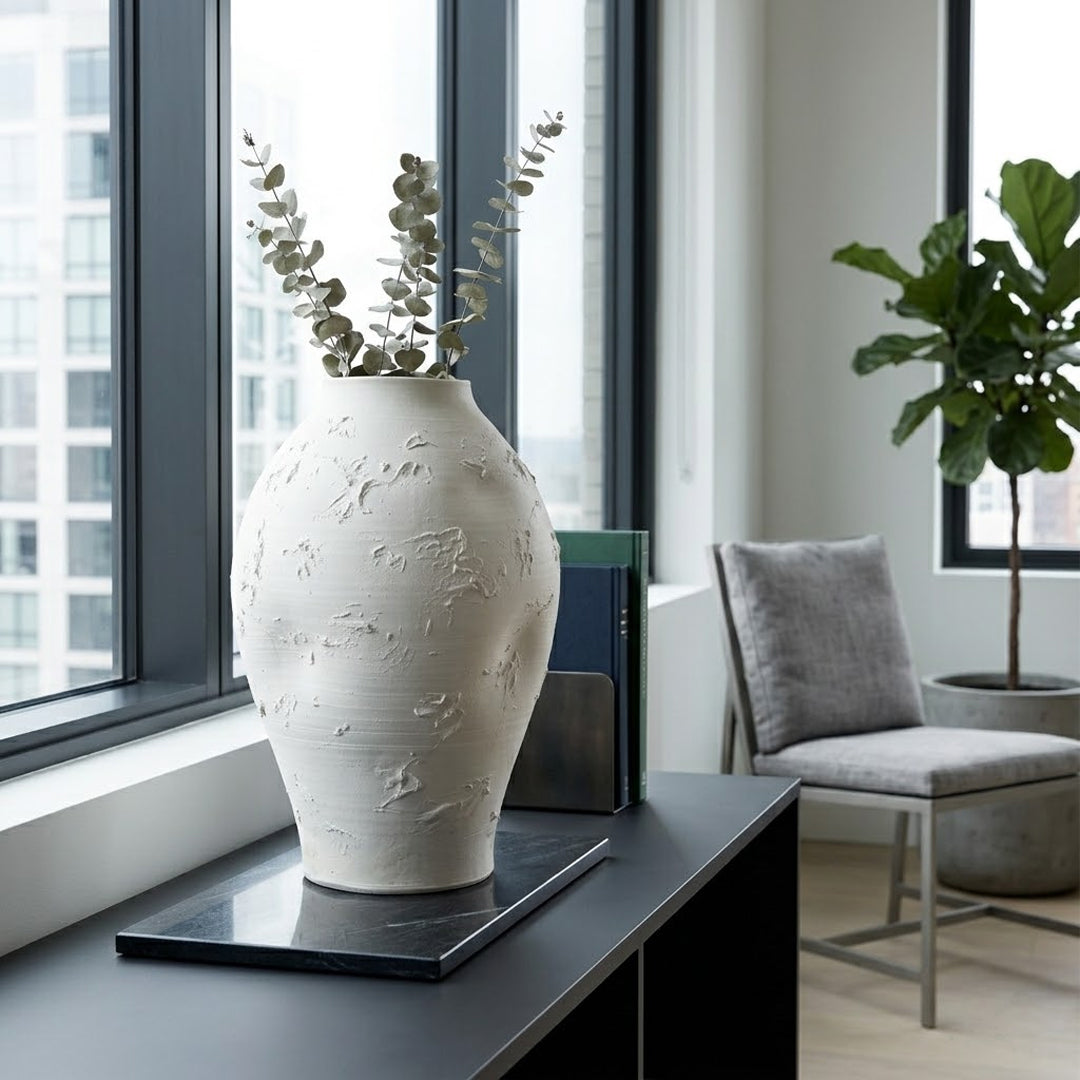 Sculptural white ceramic vase displayed on dark console table for elegant modern home decor and refined living space.