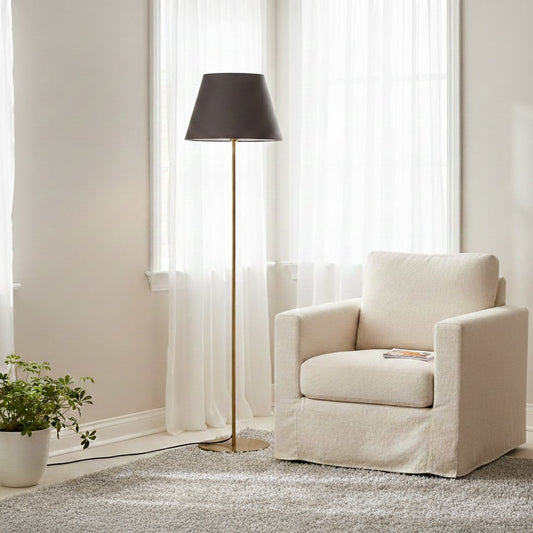 Modern gold metal floor lamp with dark grey fabric shade placed near armchair in elegant living room for soft ambient lighting Decor.