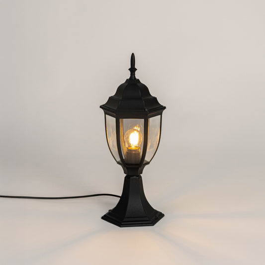 Black metal outdoor gate light with glowing bulb and clear glass shade for modern decor use.