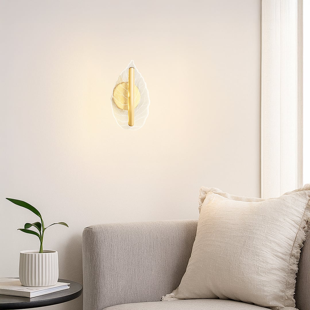 Gold metal and clear glass leaf wall light styled in a modern living room offering soft ambient decor accent lighting for home.
