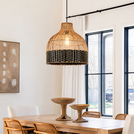 A woven rattan pendant light with a black beaded fringe, hanging over a wooden dining table in a bright, modern dining room.