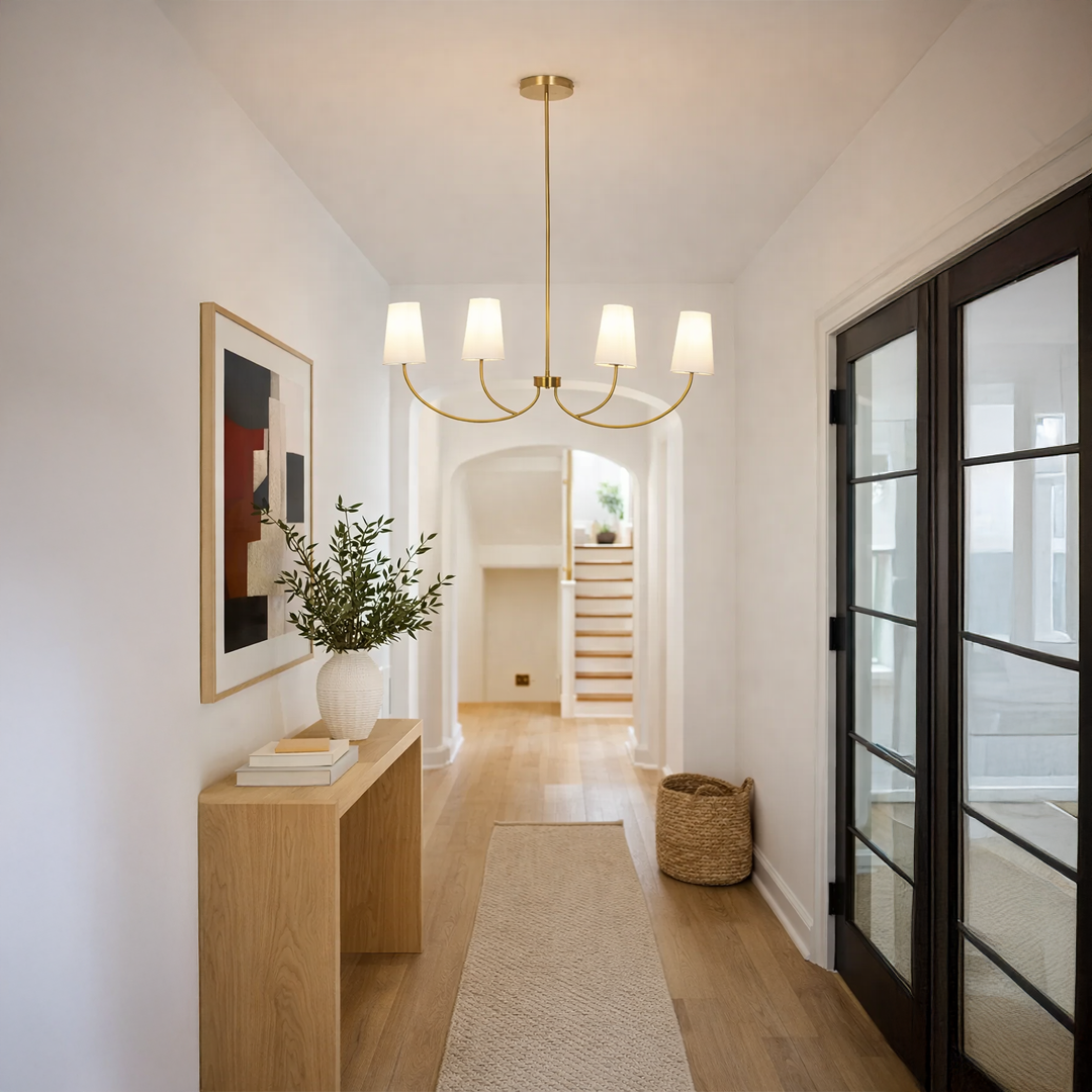 Gold metal chandelier with fabric drum shades creating warm ambient lighting in a modern hallway with elegant decor.