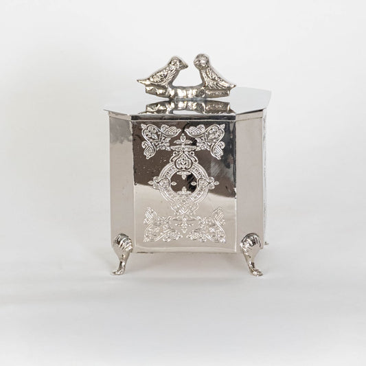 Classic silver metal trinket box with raised patterns and bird top on white background perfect for elegant home Decor.