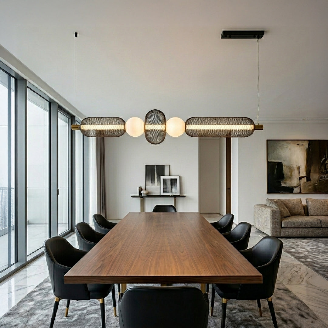Horizontal pendant light with textured glass shades and metal accents installed above dining table in modern kitchen interior setting.